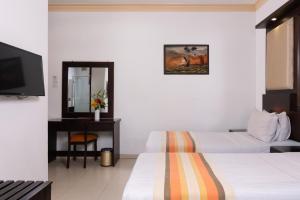 a hotel room with two beds and a mirror at Oak Ray Serene Garden Hotel in Kandy