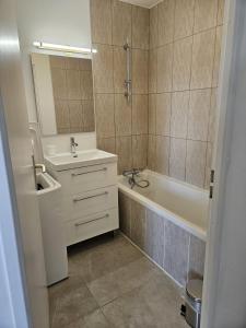 a bathroom with a sink and a tub and a mirror at La maison de Pommard in Dijon