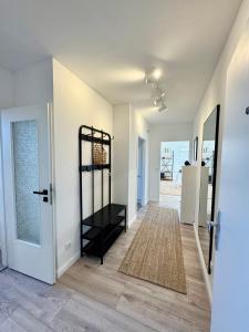 a hallway with white walls and a black shelf at Vollmöbliertes Apartment am Deich in Neuendeich