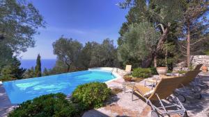 a swimming pool in a garden with chairs and a table at Villa Petra in Arvanitakaíïka