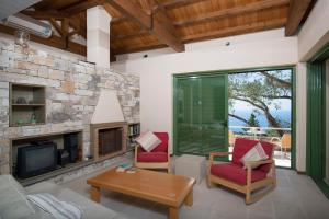 a living room with a stone fireplace and red chairs at Villa Petra in Arvanitakaíïka