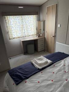 a bedroom with a bed with a desk and a window at Diamond Touch Home in Saint Osyth +21 photos