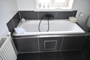 a bath tub in a bathroom with black and white tiles at Huis van de Koekuit in Moorslede +36 photos