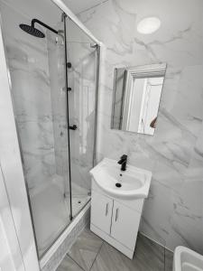 a white bathroom with a shower and a sink at London Duo & Quad Rooms in Zone 2 - Willesden Green in London