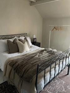 a bedroom with a large bed with white sheets and pillows at Poets Cottage Eglwys Fach in Scyborycoed