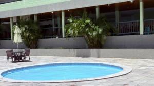 a swimming pool with a table and a chair next to a building at Flat em Gravatá - Villa Monte Castelo in Sairé