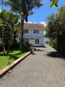 a white house with a palm tree and a driveway at City Retreat Mega in Arusha