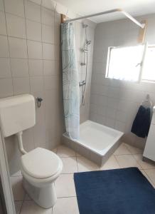 a white bathroom with a toilet and a shower at Ciprus nyaraló in Szarvas
