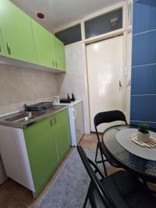 a small kitchen with green cabinets and a table at Apartmani Central Vrnjačka Banja Šetalište in Vrnjačka Banja