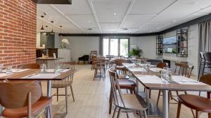 a restaurant with tables and chairs and a brick wall at Campanile Brest - Gouesnou Aeroport in Gouesnou