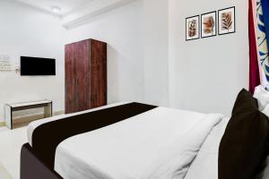 a bedroom with a white bed and a television at Hotel O CITY INN in Kolkata