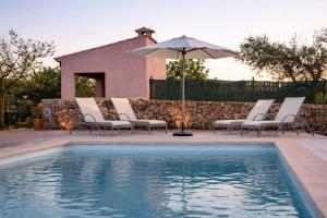 a group of chairs and an umbrella next to a pool at Petit Son Bauló in Can Picafort