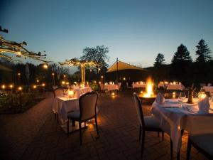 a group of tables and chairs with lights at night at Restaurant-Hotel Haus Mühlenbrock in Schermbeck