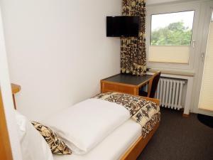 a bedroom with a bed and a desk and a window at Restaurant-Hotel Haus Mühlenbrock in Schermbeck