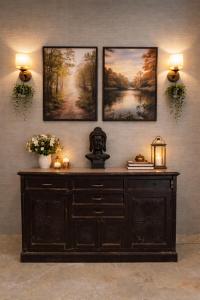 a wooden dresser in a room with three pictures on the wall at The Machan Farmhouse in Noida