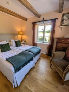 a bedroom with a bed and a chair and a window at Farmors Lycka in Kivik