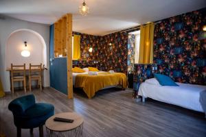 a bedroom with two beds and a table and a chair at Logis Hotels - Auberge de l'Île - Hôtel 3 étoiles et Restaurant in Creysse