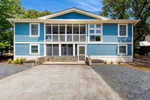 a blue house with a large driveway in front of it at Sandy Feet Retreat in Kill Devil Hills