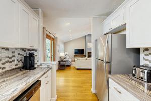 a kitchen with white cabinets and a stainless steel refrigerator at Sandy Feet Retreat in Kill Devil Hills
