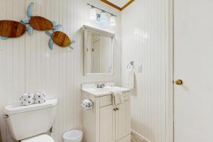 a bathroom with a toilet and a sink and a mirror at Sandy Feet Retreat in Kill Devil Hills +16 photos