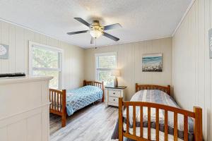 a bedroom with two twin beds and a ceiling fan at Sandy Feet Retreat in Kill Devil Hills