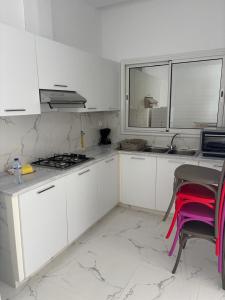 a kitchen with white cabinets and a table and a window at Résidence Molka Yasmine Hammamet in Hammamet