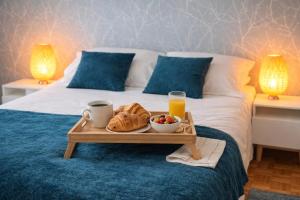 a tray with a breakfast of croissants and fruit on a bed at Le Mans Cosy in Le Mans