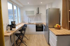 a kitchen with a refrigerator and a counter with a bowl of fruit at Le Mans Cosy in Le Mans