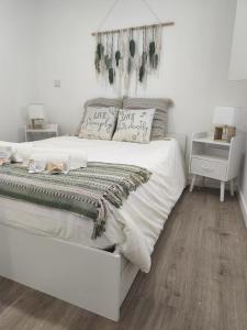 a bedroom with a white bed with plants on the wall at Valma GuestHouse in Viana do Castelo