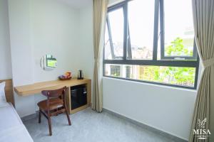 a room with a desk and a bed and a window at MISA Hotel in Dong Hoi