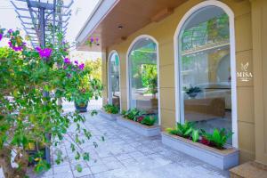 a building with arched windows and plants and flowers at MISA Hotel in Dong Hoi