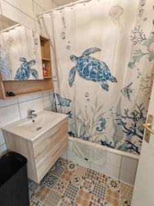 a bathroom with a turtle shower curtain and a sink at Superbe cocon de 44m2 in Longvic +11 photos