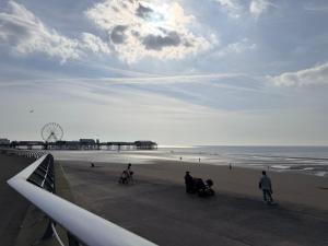 a group of people on a beach with a pier at Melrose Hotel in Blackpool