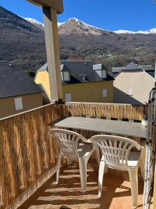 a wooden deck with a table and two chairs at Charmant appartement avec vue montagne in Luz-Saint-Sauveur