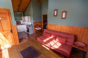 a living room with a red couch and a kitchen at Cabañas Lago Tyndall in Torres del Paine +40 photos