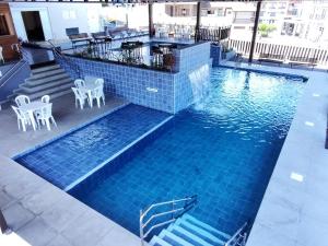 a pool with chairs and tables in a building at Caxias Thermas Hotel in Piratuba