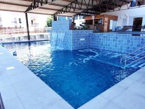 a swimming pool with blue tiles in a building at Caxias Thermas Hotel in Piratuba