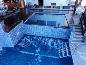 a swimming pool with a blue tiled floor and stairs at Caxias Thermas Hotel in Piratuba +43 photos