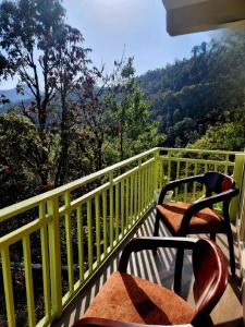 a balcony with two chairs and a view of the mountains at Mountain Golden Ray in Mukteshwar