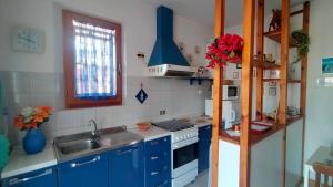 a kitchen with blue cabinets and a sink and a stove at TRILOCALE CON GIARDINO E POSTO AUTO- cod 504 in Marcelli