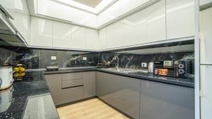 a kitchen with white cabinets and black counter tops at 7even Boutique Hostel in Tirana