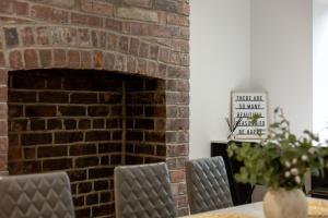 a brick fireplace in a dining room with a table and chairs at Potovens Place in Lofthouse Gate +19 photos