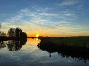a sunset over a river with the sun setting in the distance at Ferienhof Ohlenbusch in Worpswede +3 photos