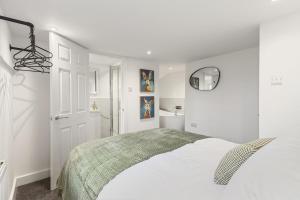 a white bedroom with a bed and a mirror at Potovens Place in Lofthouse Gate