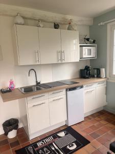a kitchen with white cabinets and a sink at Le Poule House in Guérard +6 photos