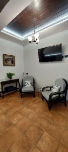 a living room with two chairs and a flat screen tv at Hotel y Restaurante Posada Real in Quetzaltenango +22 photos