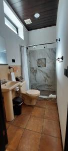 a bathroom with a shower and a toilet and a sink at Hotel y Restaurante Posada Real in Quetzaltenango