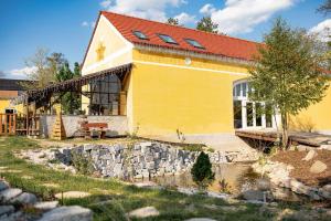 a yellow house with a stone wall next to a pond at Farma Mlýn Drásov in Drásov +91 photos