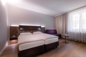 a bedroom with a large bed and a purple chair at City Hotel Stockerau in Stockerau +28 photos