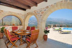 a dining room with a table and chairs and a pool at Villa Georgia in Fílippos